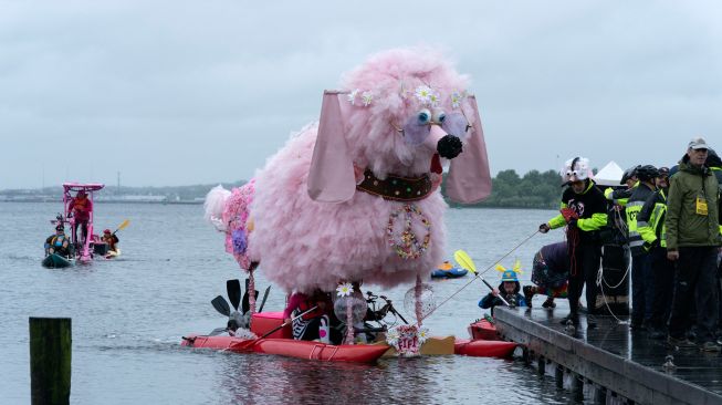 Para peserta mengayuh patung kinetik mereka di atas air saat ajang Lomba Balap Patung Kinetik yang digelar Museum Seni Visioner Amerika di Pelabuhan Baltimore, Maryland, Amerika Serikat, Sabtu (7/5/2022). [Jose Luis Magana / AFP]
