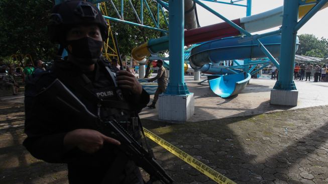 Polisi berjaga di lokasi ambrolnya seluncuran wahana permainan air di Kenjeran Water Park, Surabaya, Jawa Timur, Sabtu (7/5/2022). [ANTARA FOTO/Didik Suhartono/tom]