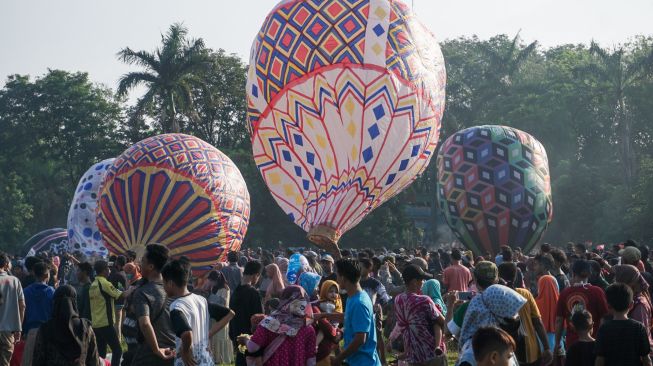 Sejumlah warga menerbangkan balon udara yang ditambatkan di tanah saat "Balloon Attraction Pekalongan 2022" di Lapangan Mataram, Kota Pekalongan, Jawa Tengah, Minggu (8/5/2022). [ANTARA FOTO/Harviyan Perdana Putra/aww]
