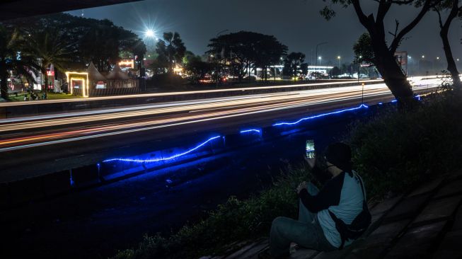 Seorang warga merekam kendaraan pemudik yang melintas menuju arah Jabodetabek di Jalan Tol Jakarta-Cikampek, Karawang, Jawa Barat, Sabtu (7/5/2022). [ANTARA FOTO/Aprillio Akbar/tom]
