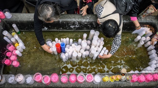 Para jemaah mempersembahkan lilin setelah kebaktian saat peraayan Hari Kelahiran Buddha di Kuil Jogye, Seoul, Korea Selatan, Minggu (8/5/2022). [ANTHONY WALLACE / AFP]
