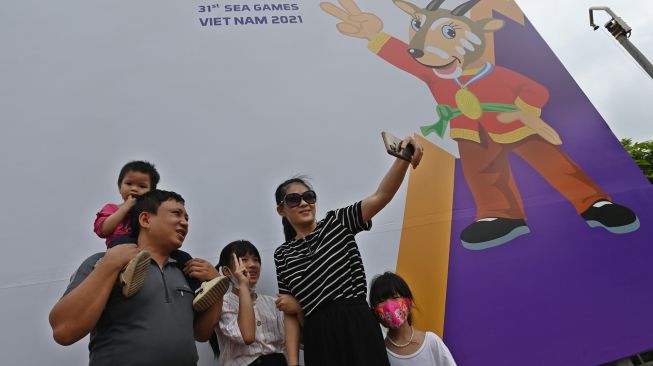 Warga berswa foto dengan latar belakang gambar maskot SEA Games 2021 Vietnam, Hanoi Saola, di Kota Hanoi, Vietnam, Minggu (8/5/2022). [ANTARA FOTO/Aditya Pradana Putra/YU]