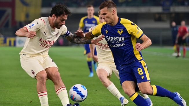 Bek AC Milan Davide Calabria (kiri) dan gelandang Hellas Verona Darko Lazovic berebut bola saat pertandingan sepak bola Serie A Liga Italia antara Hellas Verona melawan AC Milan di Stadion Marcantonio Bentegodi, Verona, Italia, Minggu (8/5/2022). [Miguel MEDINA / AFP]