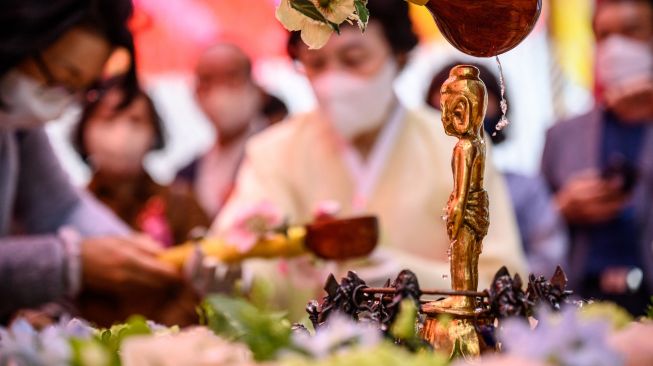 Umat Buddha mencuci patung Buddha selama kebaktian saat peraayan Hari Kelahiran Buddha di Kuil Jogye, Seoul, Korea Selatan, Minggu (8/5/2022). [ANTHONY WALLACE / AFP]