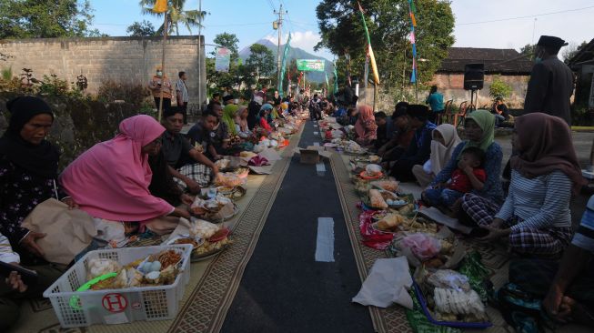 Warga mengalungkan ketupat pada hewan ternak sapi miliknya saat Tradisi Lebaran Sapi di lereng Gunung Merapi, Mlambong, Sruni, Musuk, Boyolali, Jawa Tengah, Senin (9/5/2022). [ANTARA FOTO/Aloysius Jarot Nugroho/rwa]