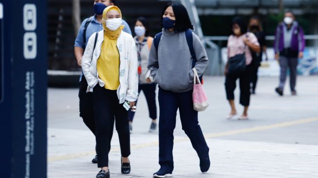 Sejumlah pekerja berjalan di trotoar saat jam pulang kerja di Jalan Sudirman, Jakarta Pusat, Senin (9/5/2022). [Suara.com/Alfian Winanto]