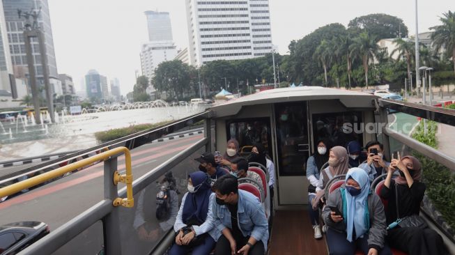 Warga berada di atas bus wisata gratis Transjakarta dengan atap terbuka di Jakarta, Selasa (10/5/2022). [Suara.com/Angga Budhiyanto]