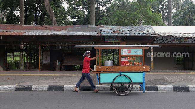 Seorang pedagang berjalan melintasi deretan kios pedagang di Pasar Hewan Barito, Kebayoran Baru, Jakarta, Selasa (10/5/2022). [Suara.com/Angga Budhiyanto]