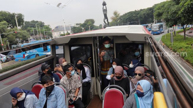 Warga berada di atas bus wisata gratis Transjakarta dengan atap terbuka di Jakarta, Selasa (10/5/2022). [Suara.com/Angga Budhiyanto]