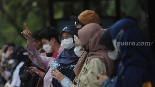 Warga menunggu kedatangan bus wisata gratis Transjakarta di Jakarta, Selasa (10/5/2022). [Suara.com/Angga Budhiyanto]