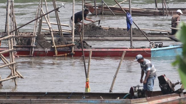 Pekerja menambang pasir menggunakan perahu di tengah aliran sungai Brantas, Kota Kediri, Jawa Timur, Rabu (11/5/2022). ANTARA FOTO/Prasetia Fauzani