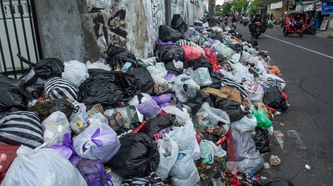 Pengendara melintas di dekat tumpukan sampah di kawasan Patuk, Yogyakarta, Rabu (11/5/2022). ANTARA FOTO/Hendra Nurdiyansyah