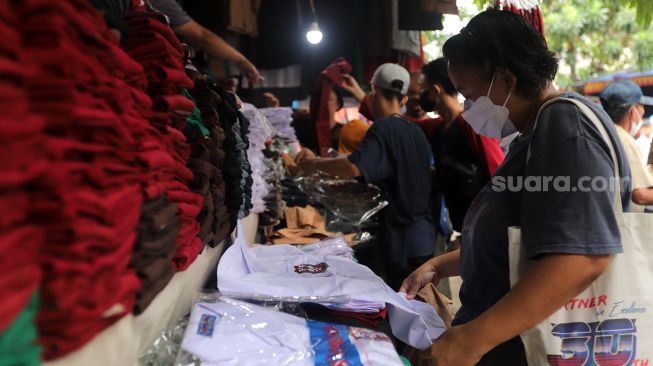 Calon pembeli memilih seragam sekolah di Pasar Jatinegara, Jakarta, Rabu (11/5/2022). [Suara.com/Angga Budhiyanto]