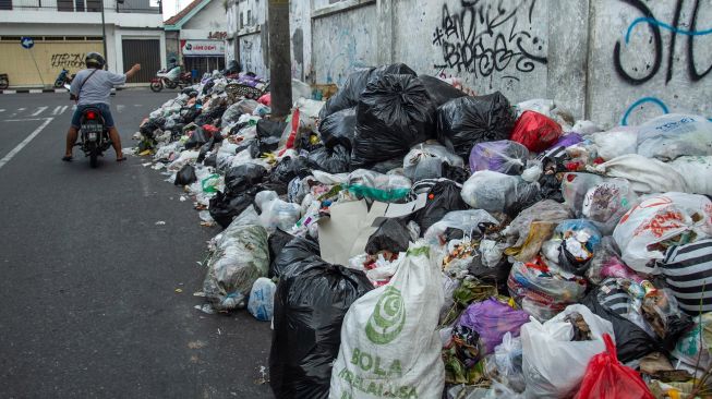 Pengendara melintas di dekat tumpukan sampah di kawasan Patuk, Yogyakarta, Rabu (11/5/2022). ANTARA FOTO/Hendra Nurdiyansyah