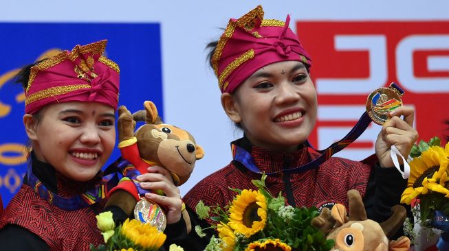 Pesilat Indonesia Riska Hermawan (kiri) dan Ririn Rinasih (kanan) berpose dengan medali emasnya yang diraih pada final Seni Ganda Putri Pencak Silat SEA Games 2021 Vietnam di Bac Tu Liem Sport Center, Hanoi, Rabu (11/5/2022).  ANTARA FOTO/Zabur Karuru