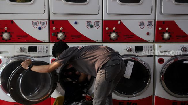 Pekerja membersihkan baju pelanggan di Jourdan Laundry Expert, Ampera Raya, Jakarta, Rabu (11/5/2022). [Suara.com/Angga Budhiyanto]