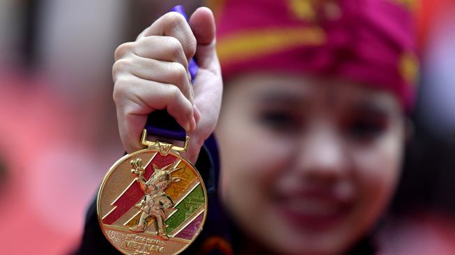 Pesilat Indonesia Riska Hermawan menunjukkan medalinya emas yang diraih pada final Seni Ganda Putri Pencak Silat SEA Games 2021 Vietnam di Bac Tu Liem Sport Center, Hanoi, Rabu (11/5/2022). ANTARA FOTO/Zabur Karuru