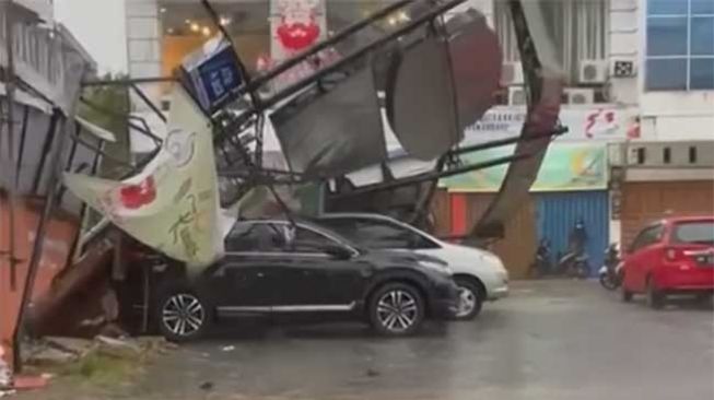 Hujan Disertai Angin Kencang, Papan Reklame Tumbang Timpa 2 Mobil di Pekanbaru