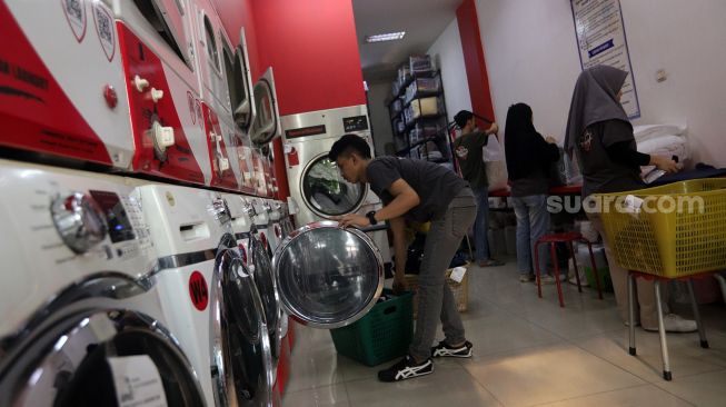 Pekerja membersihkan baju pelanggan di Jourdan Laundry Expert, Ampera Raya, Jakarta, Rabu (11/5/2022). [Suara.com/Angga Budhiyanto]