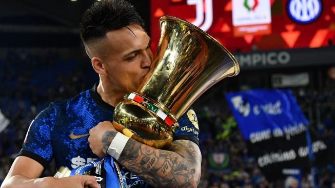 Penyrrang Inter Milan, Lautaro Martinez mencium trofi Coppa Italia. [Isabella BONOTTO / AFP]