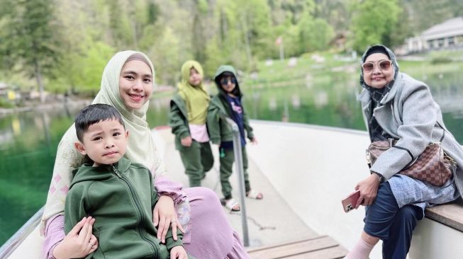 Oki Setiana Dewi bersama suami, Ory Vitrio, empat anaknya dan sang ibu berlibur di Danau Blausee, Swiss. [Instagram]