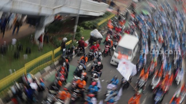 Sejumlah massa buruh melakukan 'long march' menuju Stadion Gelora Bung Karno usai berunjuk rasa di depan gedung DPR RI, Jakarta, Sabtu (14/5/2022). [Suara.com/Angga Budhiyanto]