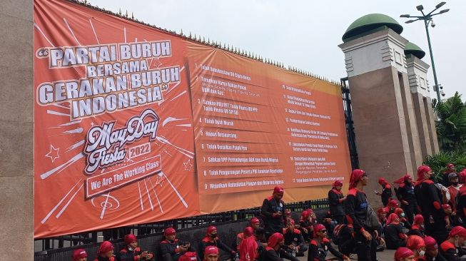 Massa Partai Buruh dan Gerakan Buruh Indonesia membentangkan spanduk raksasa di pintu gerbang Gedung DPR RI, Senayan, Jakarta, Sabtu (14/5/2022).