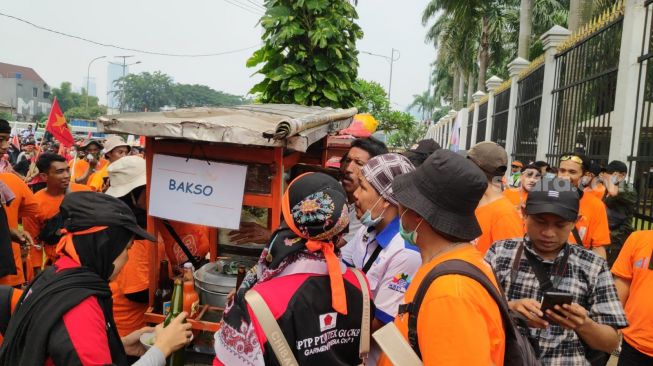 Massa buruh langsung menyerbu pedagang bakso yang telah diborong oleh Kapolda Metro Jaya Irjen Fadil Imran untuk mereka di depan Gedung DPR, Jakarta, Sabtu (14/5/2022). [Suara.com/Bagaskara Isdiansyah]