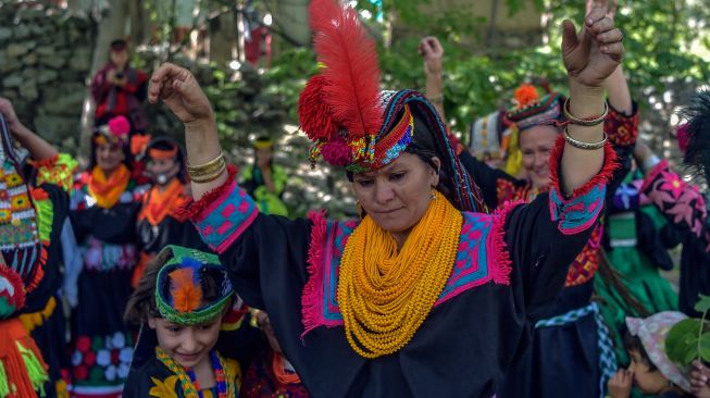 Wanita suku Kalash yang mengenakan pakaian tradisional menari pada hari pertama festival 'Joshi' di desa Bumburet, Pakistan, Sabtu (14/5/2022). [Abdul MAJEED / AFP]
