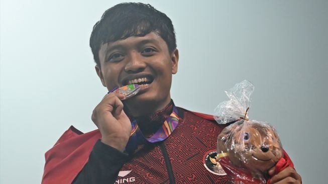 Atlet Indonesia Abdul Hafiz menggigit medalinya usai pengalungan medali nomor lempar lembing putra SEA Games 2021 Vietnam di Stadion Nasional My Dinh, Hanoi, Vietnam, Sabtu (14/5/2022). [ANTARA FOTO/Aditya Pradana Putra/aww]
