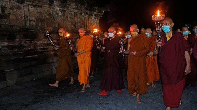 Sejumlah Bhiksu melakukan Pradaksina atau berjalan mengelilingi candi saat prosesi penyemayaman Api Dharma dalam rangkaian perayaan Tri Suci Waisak 2566 BE/2022 di Candi Mendut, Mungkid, Magelang, Jateng, Sabtu (14/5/2022). [ANTARA FOTO/Anis Efizudin/aww]
