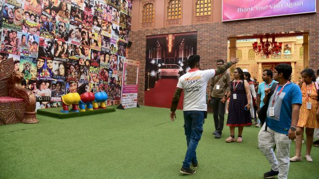 Seorang pemandu (kiri) memimpin sekelompok pengunjung selama tur di Taman Bollywood di Filmcity Mumbai, India, Jumat (13/5/2022). [SUJIT JAISWAL / AFP]