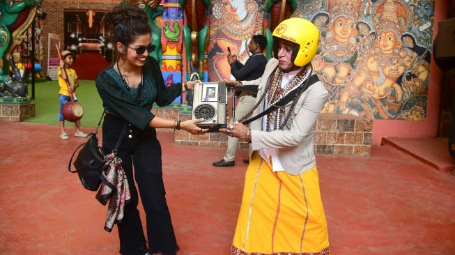 Seorang pengunjung berswafoto dengan seorang pekerja taman yang berpakaian seperti karakter film Bollywood Amir Khan saat berkunjung di Taman Bollywood di Filmcity Mumbai, India, Jumat (13/5/2022). [SUJIT JAISWAL / AFP]