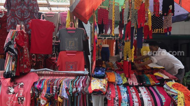 Pedagang merapikan pakaian di lapaknya di Pasar Petak Sembilan, Glodok, Jakarta, Senin (16/5/2022). [Suara.com/Angga Budhiyanto]