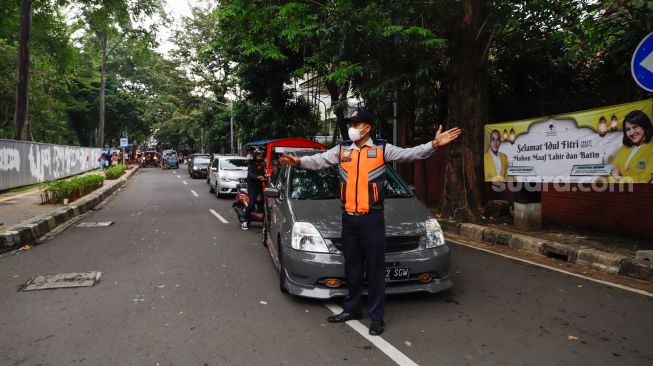 Petugas mengatur kendaraan saat melakukan uji coba rekayasa lalu lintas di sekitar kawasan Tebet Eco Park, Jakarta Selatan, Senin (16/5/2022). [Suara.com/Alfian Winanto]
