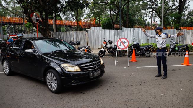 Petugas mengatur kendaraan saat melakukan uji coba rekayasa lalu lintas di sekitar kawasan Tebet Eco Park, Jakarta Selatan, Senin (16/5/2022). [Suara.com/Alfian Winanto]
