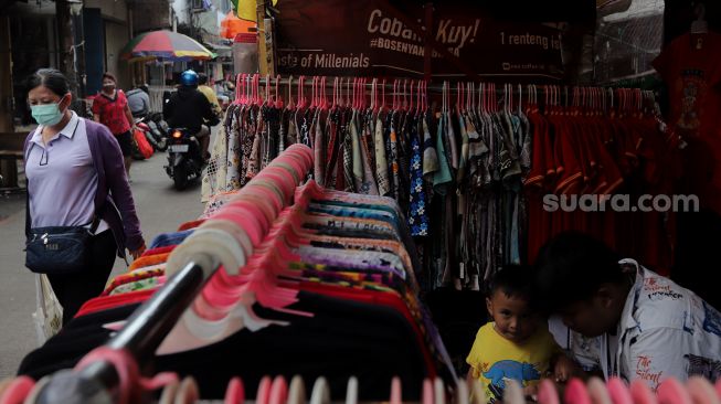 Warga melintasi lapak pedagang kaki lima (PKL) di Pasar Petak Sembilan, Glodok, Jakarta, Senin (16/5/2022). [Suara.com/Angga Budhiyanto]