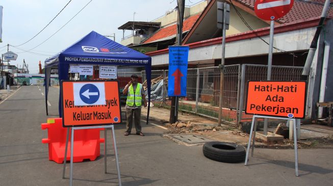 Pekerja berjaga di pos pengamanan saat rekayasa lalu lintas di Jalan Otista 3 terkait pekerjaan pembangunan sodetan kali Ciliwung ke Kanal Banjir Timur, Jakarta, Senin (16/5/2022). ANTARA FOTO/Reno Esnir