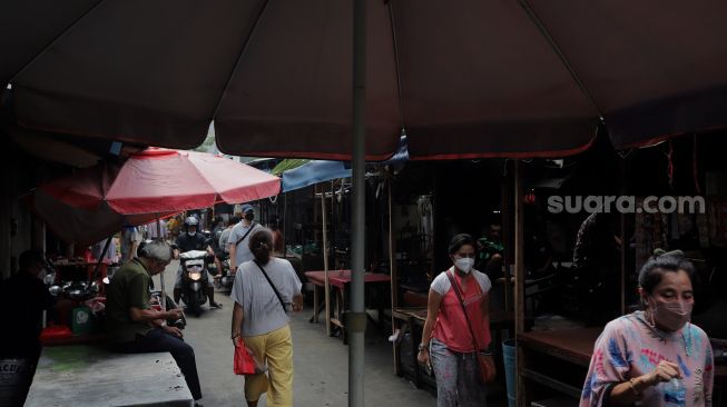 Warga melintasi lapak pedagang kaki lima (PKL) di Pasar Petak Sembilan, Glodok, Jakarta, Senin (16/5/2022). [Suara.com/Angga Budhiyanto]