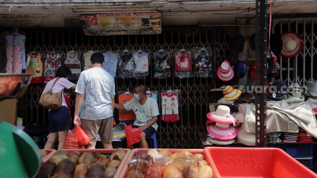 Pedagang melayani pembeli di Pasar Petak Sembilan, Glodok, Jakarta, Senin (16/5/2022). [Suara.com/Angga Budhiyanto]