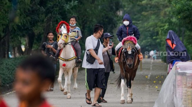 Anak-anak berwisata sambil menunggangi kuda di kawasan Kanal Banjir Timur (KBT), Jakarta Timur, Senin (16/5/2022). [Suara.com/Alfian Winanto] 