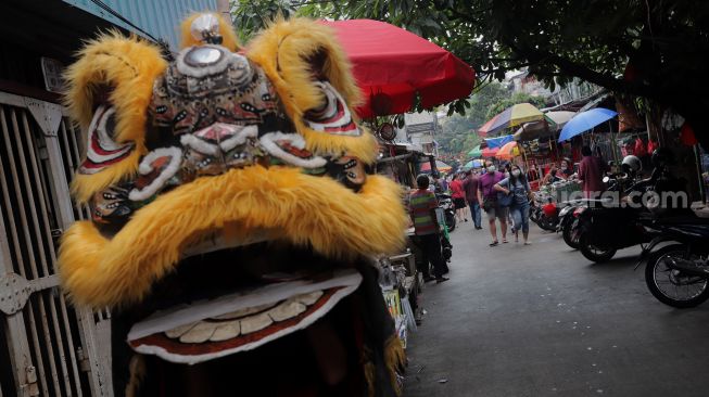 Pengamen mengenakan kostum barongsai mencari nafkah di Pasar Petak Sembilan, Glodok, Jakarta, Senin (16/5/2022). [Suara.com/Angga Budhiyanto]