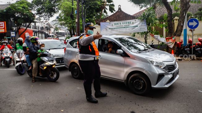 Petugas mengatur kendaraan saat melakukan uji coba rekayasa lalu lintas di sekitar kawasan Tebet Eco Park, Jakarta Selatan, Senin (16/5/2022). [Suara.com/Alfian Winanto]
