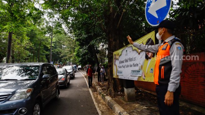 Petugas mengatur kendaraan saat melakukan uji coba rekayasa lalu lintas di sekitar kawasan Tebet Eco Park, Jakarta Selatan, Senin (16/5/2022). [Suara.com/Alfian Winanto]
