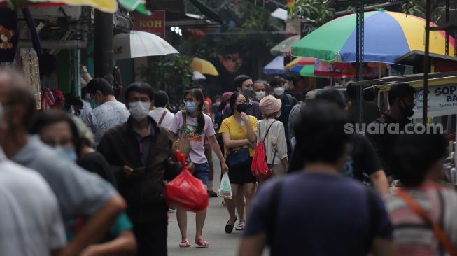 Warga melintasi lapak pedagang kaki lima (PKL) di Pasar Petak Sembilan, Glodok, Jakarta, Senin (16/5/2022). [Suara.com/Angga Budhiyanto]