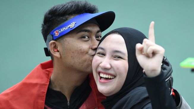 Petembak Fathur Gustafian (kiri) mencium kekasihnya yang juga petembak peraih medali emas, Dewi Laila Mubarokah (kanan), usai memenangkan nomor 10 meter air rifle (senapan angin) putra menembak SEA Games 2021 Vietnam di Hanoi Sports Training and Competition Center, Hanoi, Vietnam, Selasa (17/5/2022). ANTARA FOTO/Aditya Pradana Putra
