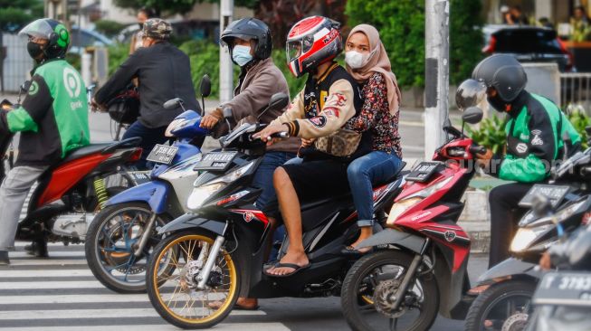 Pengendara motor berhenti saat lampu merah Jalan Thamrin, Jakarta Pusat, Selasa (17/5/2022). [Suara.com/Alfian Winanto]