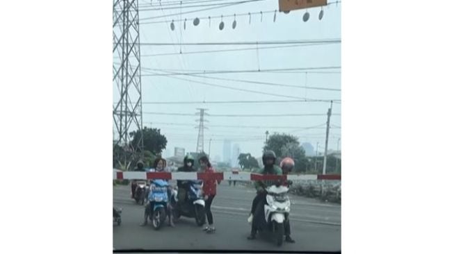 Lebih Sayang Waktu, Warga Nekat Terobos Palang Kereta Api Sampai Jatuh