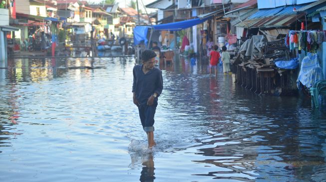 Warga melewati banjir rob yang menggenangi kawasan perkampungan nelayan di Purus Atas, Kota Padang, Sumatera Barat, Rabu (18/5/2022).  ANTARA FOTO/Iggoy el Fitra