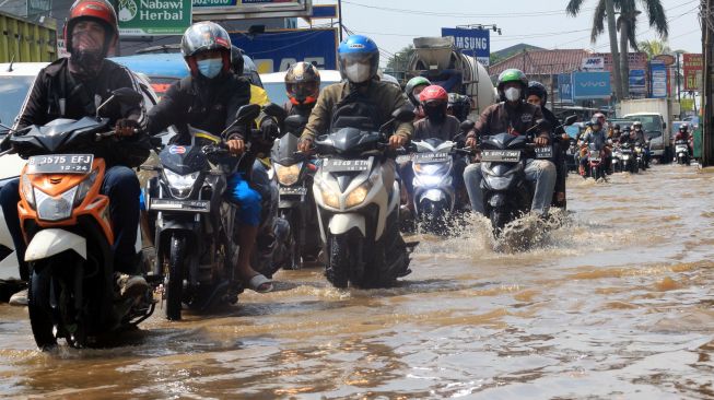 Sejumlah pengendara kendaraan menerobos genangan banjir di Jalan Raya Sawangan, Perempatan Mampang, Depok, Jawa Barat, Rabu (18/5/2022).  ANTARA FOTO/Yulius Satria Wijaya